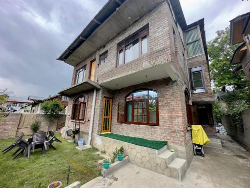 a brick house with a patio and a yard at John's Homestay in Srinagar