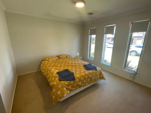a bedroom with a bed with a yellow comforter and windows at Elegant master bedroom with private bathroom in Point Cook
