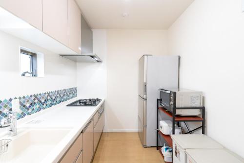 a kitchen with white counters and a refrigerator at USJ 大阪梅田駅へ15分の広々3LDK戸建 at 野田 in Osaka