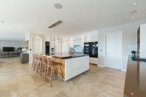 a kitchen with white cabinets and a bar with stools at 10 Bowmoor Edge By Birch Stays in Gloucestershire