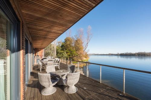 a balcony with tables and chairs on a building next to the water at 10 Bowmoor Edge By Birch Stays in Gloucestershire