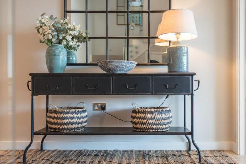 a black console table with two vases and a lamp at 10 Bowmoor Edge By Birch Stays in Gloucestershire