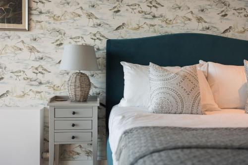 a bed with a blue headboard and a lamp on a night stand at 10 Bowmoor Edge By Birch Stays in Gloucestershire