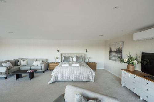 a bedroom with a bed and a couch and a tv at 10 Bowmoor Edge By Birch Stays in Gloucestershire