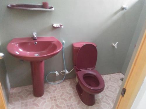 a bathroom with a red toilet and a sink at Anosha Villa in Weligama