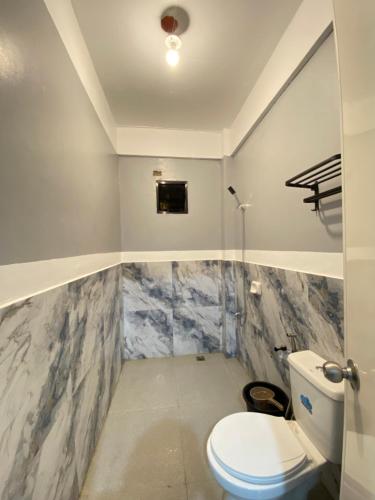 a bathroom with a white toilet and marble walls at Maicaellas Transient Room in Coron