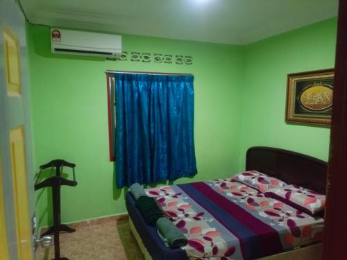 a bedroom with a bed with a blue curtain and a window at MieHomestay Binjai Rendah in Bukit Payong