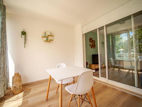 a white dining room with a white table and chairs at studio cosy - champ fleuri in Sainte-Clotilde