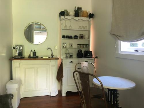 een keuken met een tafel, een wastafel en een spiegel bij Matamata Historic Cottage- The Wash-House in Matamata