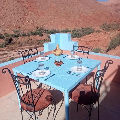 a table with four chairs and a blue table with a view at Dar Brahim Resto Beds in Ouarzazate