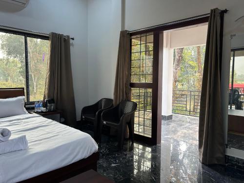 - une chambre avec un lit et deux chaises et un balcon dans l'établissement AAHI'S CHILAPATA JUNGLE STAY, à Fālākāta