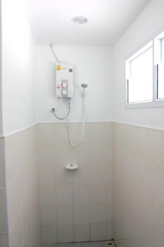 a shower in a white tiled bathroom at Cape Go Resort in Chao Lao Beach