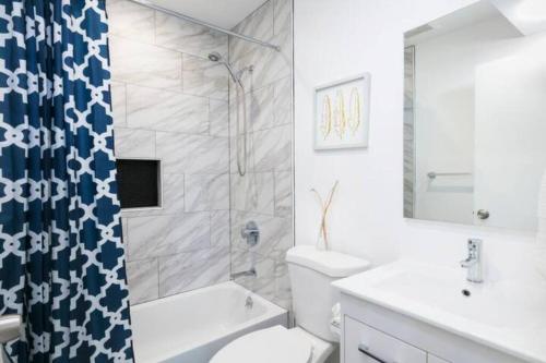 a white bathroom with a toilet and a shower at Newly Remodeled Cozy 2BR or 3BR Apartment in Tanforan, block away from CalTrain, near SFO in San Bruno