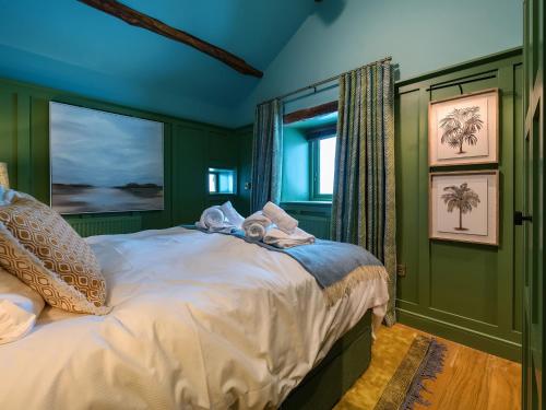 a bedroom with green walls and a bed with towels on it at Three Peaks Barn in Carnforth