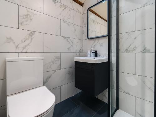 a bathroom with a toilet and a sink and a mirror at Three Peaks Barn in Carnforth