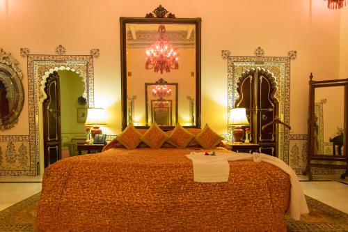 a bedroom with a large bed and a chandelier at Shiv Niwas Palace by HRH Group of Hotels in Udaipur