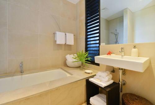 La salle de bains est pourvue d'une baignoire, d'un lavabo et d'un miroir. dans l'établissement Hapuka - Luxury Villa with Stunning Views on Murphy St, à Port Douglas