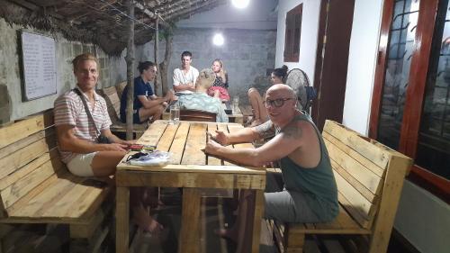 a group of people sitting around a wooden table at Anosha Villa in Weligama