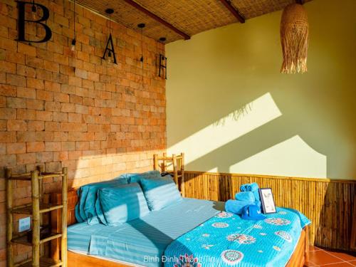 1 dormitorio con 1 cama azul y pared de ladrillo en Life's A Beach, en Quy Nhon