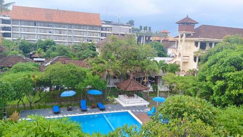 a resort with a pool and blue chairs and umbrellas at New Mekar Jaya Hotel in Legian