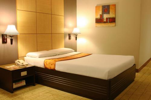 a hotel room with a bed and a telephone at Riviera Mansion Hotel in Manila