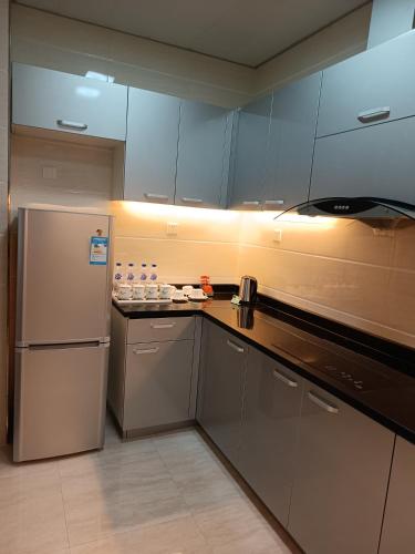 a kitchen with blue cabinets and a refrigerator at Changchun Clear Moon Apartment by South Lake Hotel in Changchun