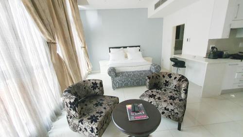 a living room with two chairs and a table and a bed at iTowers Studio-Suite in Gaborone