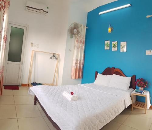 um quarto com uma grande cama branca e uma parede azul em Ly Tri Ly Son Hotel em Ly Son