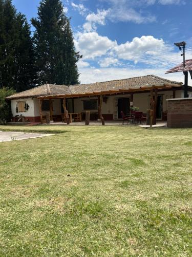 a house with a grass field in front of it at Steingarten, Casa de Campo hermosa y amoblada. in Riobamba