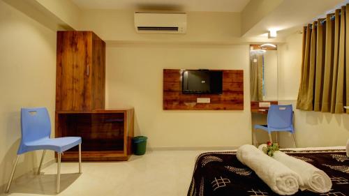 a living room with a tv and two blue chairs at HOTEL SAPPHIRE INN in Thane