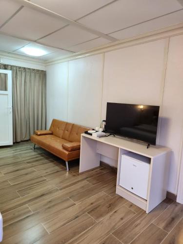 a living room with a couch and a desk with a television at Lina Dreamland Resort in Billah