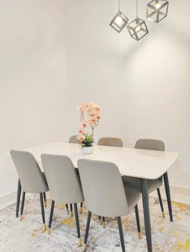 a white dining room table with chairs and a white wall at UR Homestay, Seri Iskandar in Seri Iskandar