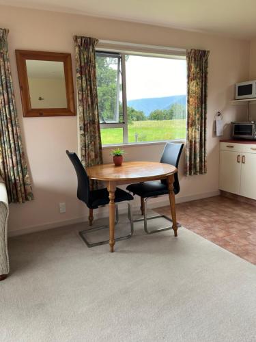 a dining room with a table and chairs and a window at Carrickfergus Cottage Unit 2 in Harihari