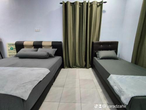 two beds in a room with green curtains at Homestay HABI Residence in Kepala Batas