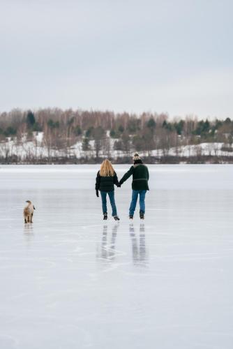 two people and a dog on a frozen lake at Living art piece at the lake. in Užutrakis