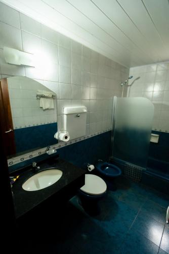 a bathroom with two toilets and a sink and a mirror at HOTEL TROPICAL IGUAZU in Puerto Iguazú