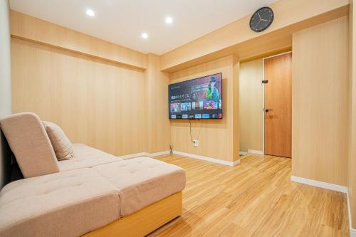 a room with a couch and a tv on a wall at Sakura Suite in Tokyo
