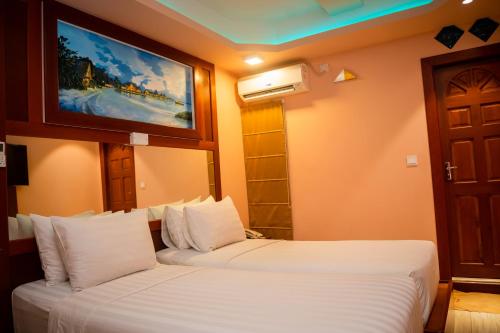 a hotel room with two beds and a painting on the wall at ZAN Lodge in Male City