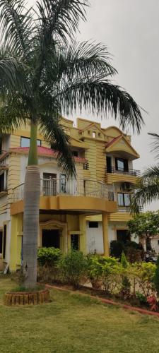 a large yellow building with a palm tree in front of it at Gaurav Resort in Rāmtek