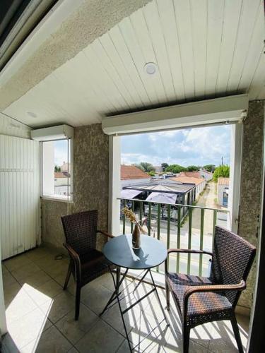 un balcon avec une table, des chaises et une fenêtre dans l'établissement L'Embellie au coeur du village de La Cotinière, à La Cotinière