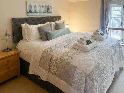 a bedroom with a large bed with towels on it at Bea Cottage in Bourton on the Water
