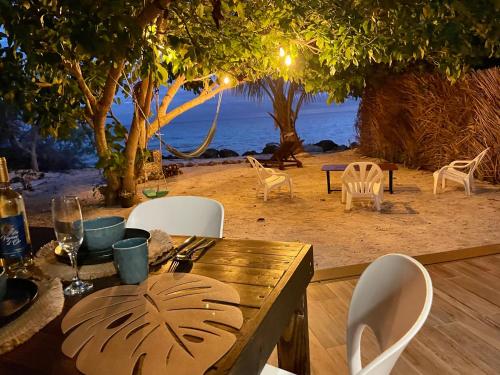 een houten tafel en stoelen met uitzicht op het strand bij Rangiroa Beach House in Avatoru