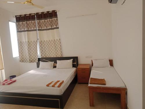 Suman beach House في تشيناي: غرفة نوم بسريرين وطاولة فيها