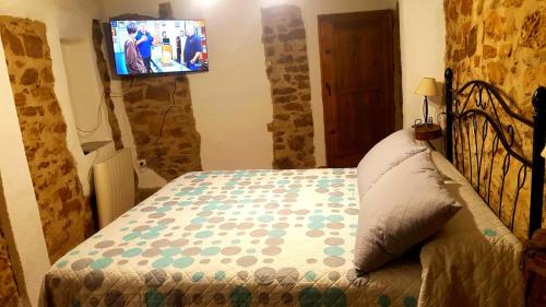 a bedroom with a bed with a tv on the wall at Casa Iván in Xert