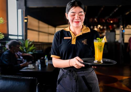 a woman holding a tray with a drink on it at ZAN Lodge in Male City