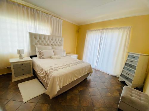 a bedroom with a bed and a dresser and windows at Third Haven in Swakopmund