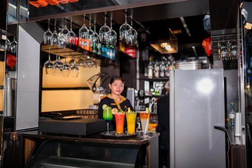 a woman standing behind a bar with some drinks at ZAN Lodge in Male City