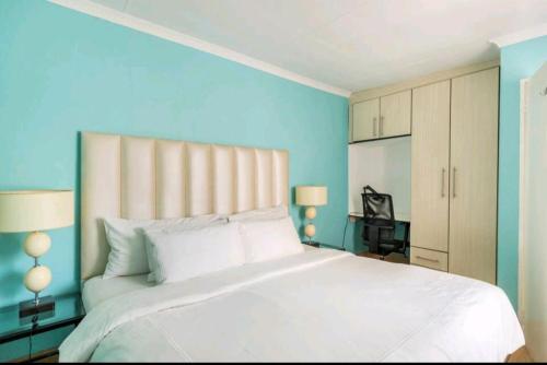 a bedroom with a large white bed with blue walls at Lovely Linden Cottage with Solar Inverter in Johannesburg