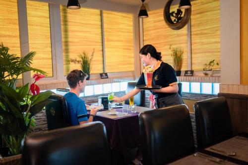 a woman serving a man at a table in a restaurant at ZAN Lodge in Male City