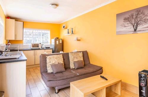 uma sala de estar com um sofá e uma cozinha em Lovely Linden Cottage with Solar Inverter em Joanesburgo